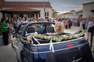 Im Cabrio kommt die Braut zur griechischen Hochzeit auf den Hof der Kirche gefahren