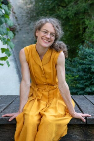 Die junge Frau sitzt an Schloss Blutenburg und lacht für ihr Portrait in die Kamera